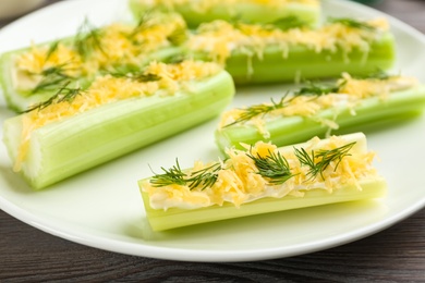 Photo of Celery sticks with sauce, cheese and dill on plate, closeup