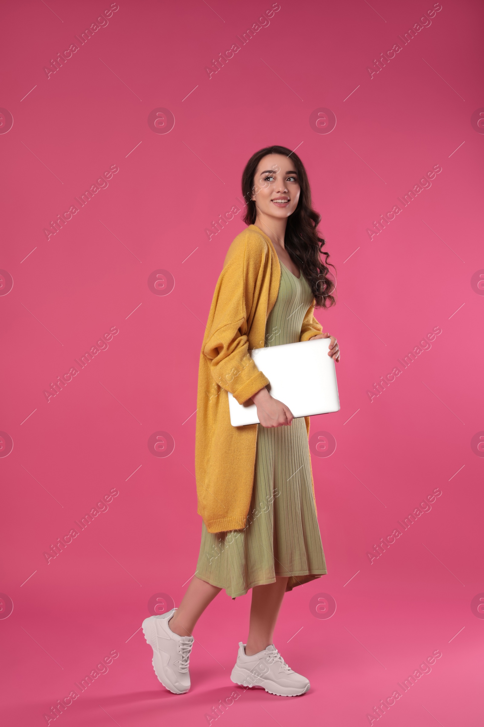 Photo of Young woman with laptop on pink background
