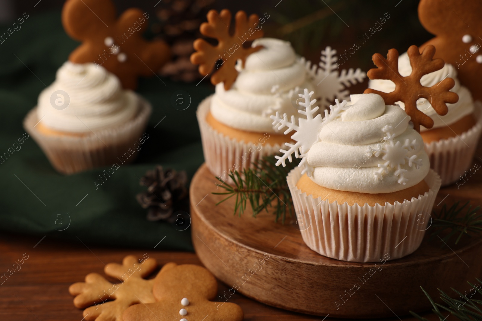 Photo of Different beautiful Christmas cupcakes and fir branches on wooden table. Space for text