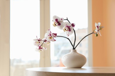 Photo of Vase with orchid flowers on white table near window indoors