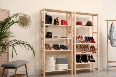 Photo of Wooden shelving unit with different shoes and accessories in stylish room interior