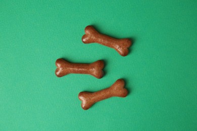 Photo of Bone shaped dog cookies on green background, flat lay