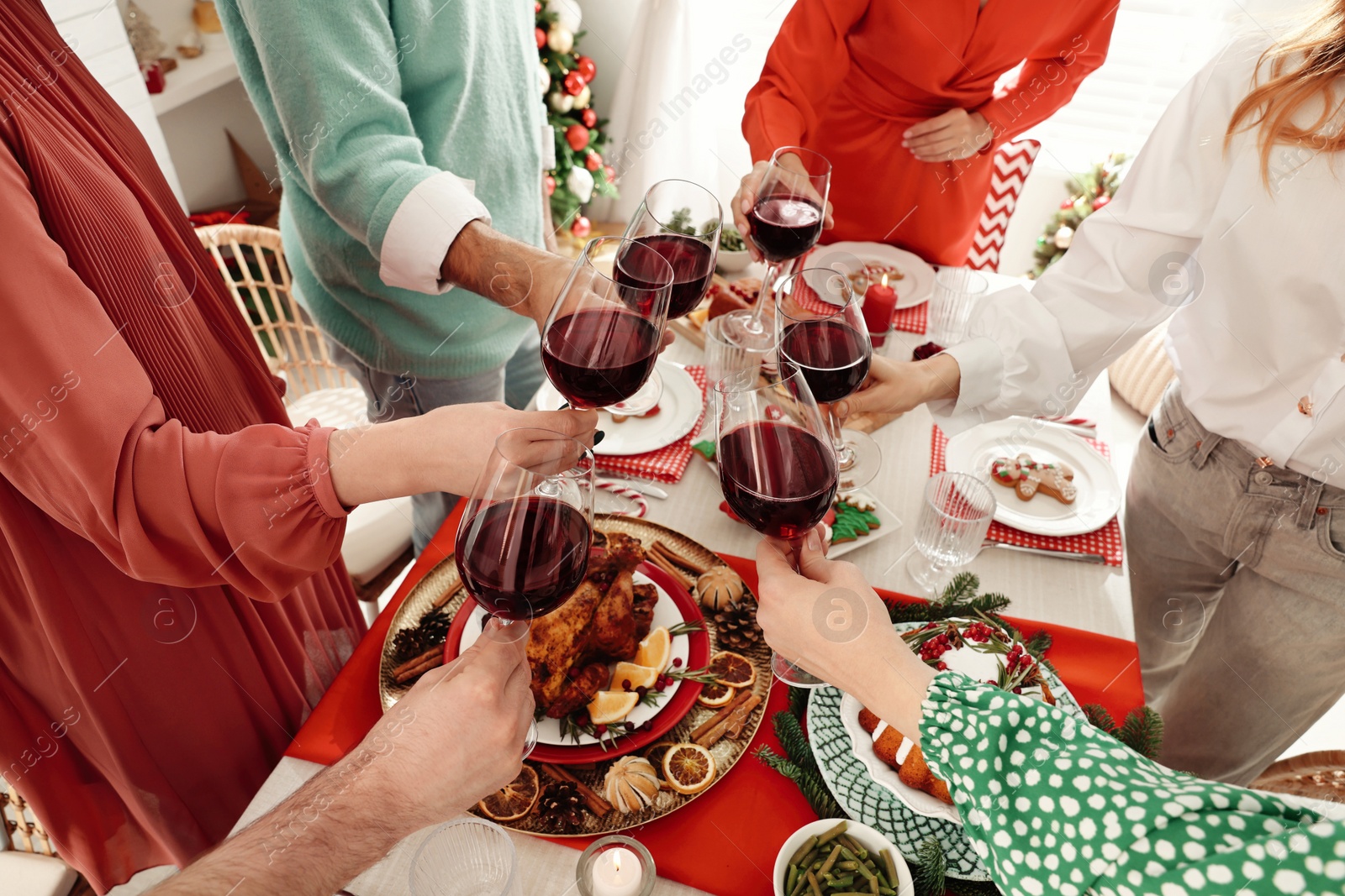 Photo of Family with their friends clinking glasses at festive dinner indoors, closeup. Christmas Eve celebration