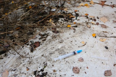 Photo of Disposable syringe with needle on concrete surface outdoors