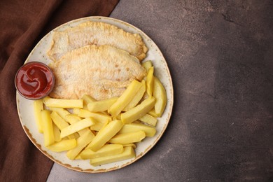 Photo of Delicious fish and chips with ketchup on brown table, top view. Space for text