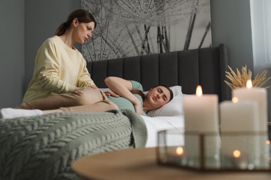 Photo of Doula taking care of pregnant woman in bedroom. Preparation for child birth