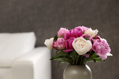 Photo of Vase with bouquet of beautiful peonies in room, space for text