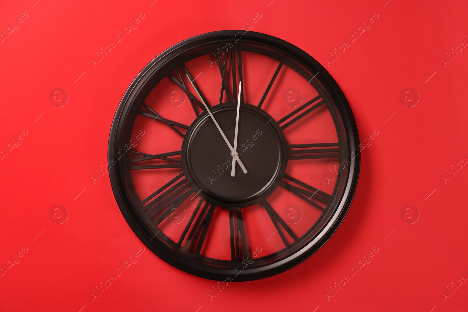 Photo of Clock showing five minutes until midnight on red background. New Year countdown