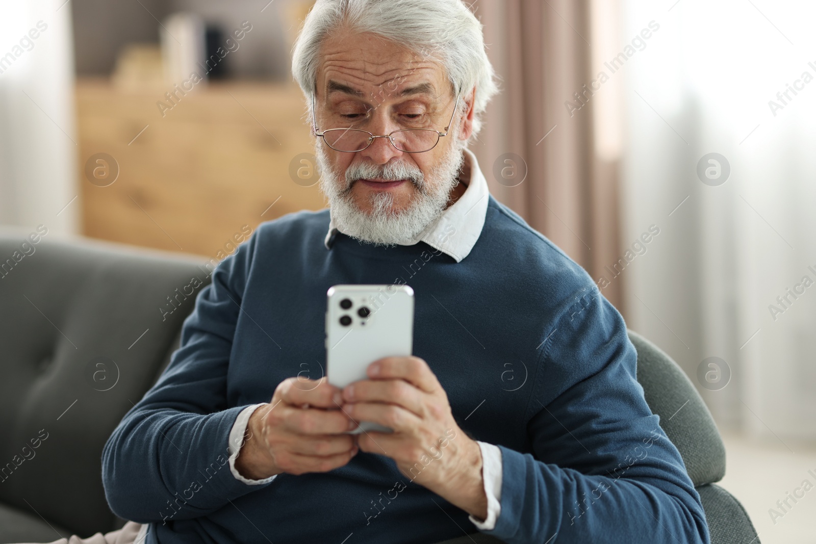 Photo of Portrait of happy grandpa with glasses using smartphone indoors