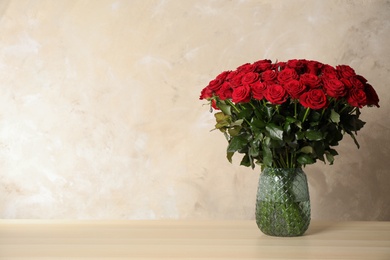 Photo of Luxury bouquet of fresh red roses wooden table, space for text