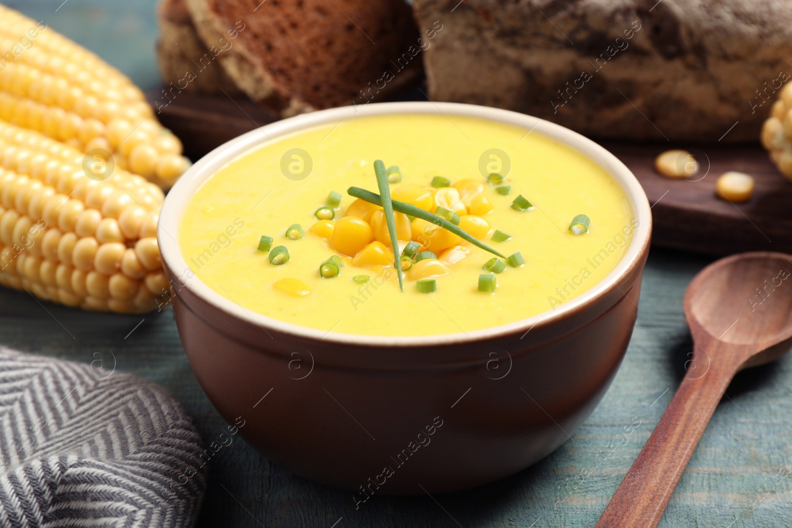 Photo of Delicious creamy corn soup served on blue wooden table