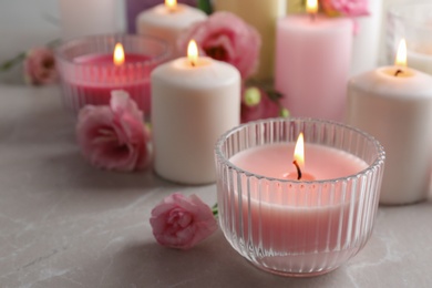 Burning candles and flowers on light grey table