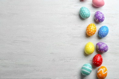 Flat lay composition of painted Easter eggs on wooden table, space for text