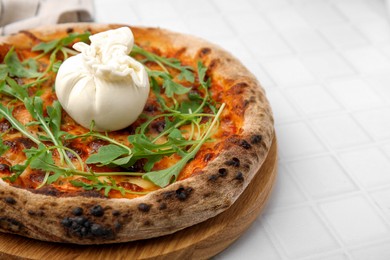 Delicious pizza with burrata cheese and arugula on white tiled table, closeup. Space for text