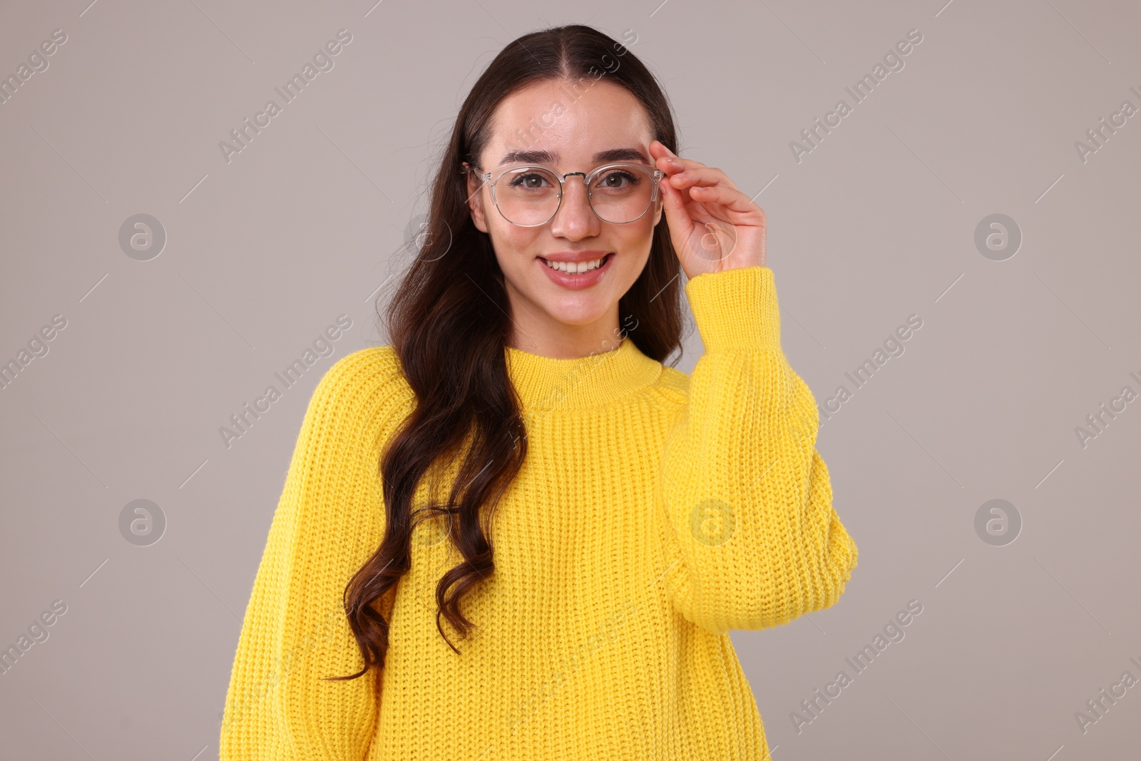 Photo of Beautiful young woman in stylish warm sweater on grey background