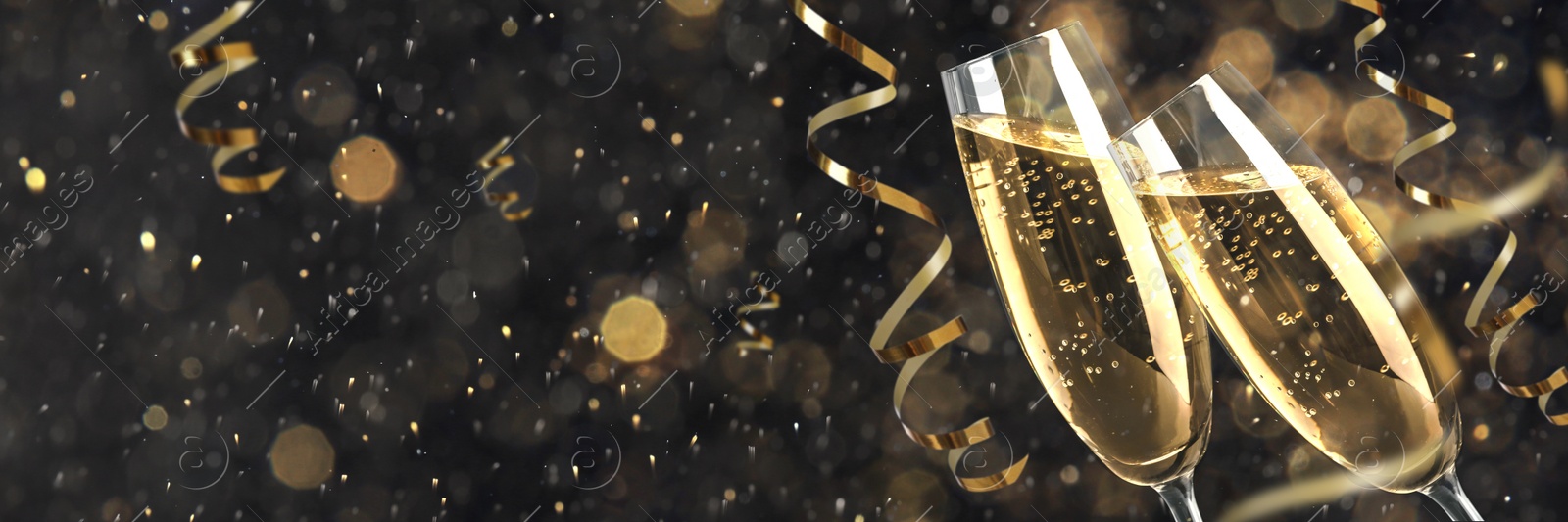 Image of Glasses with sparkling wine and shiny serpentine streamers against blurred festive lights, space for text. Banner design