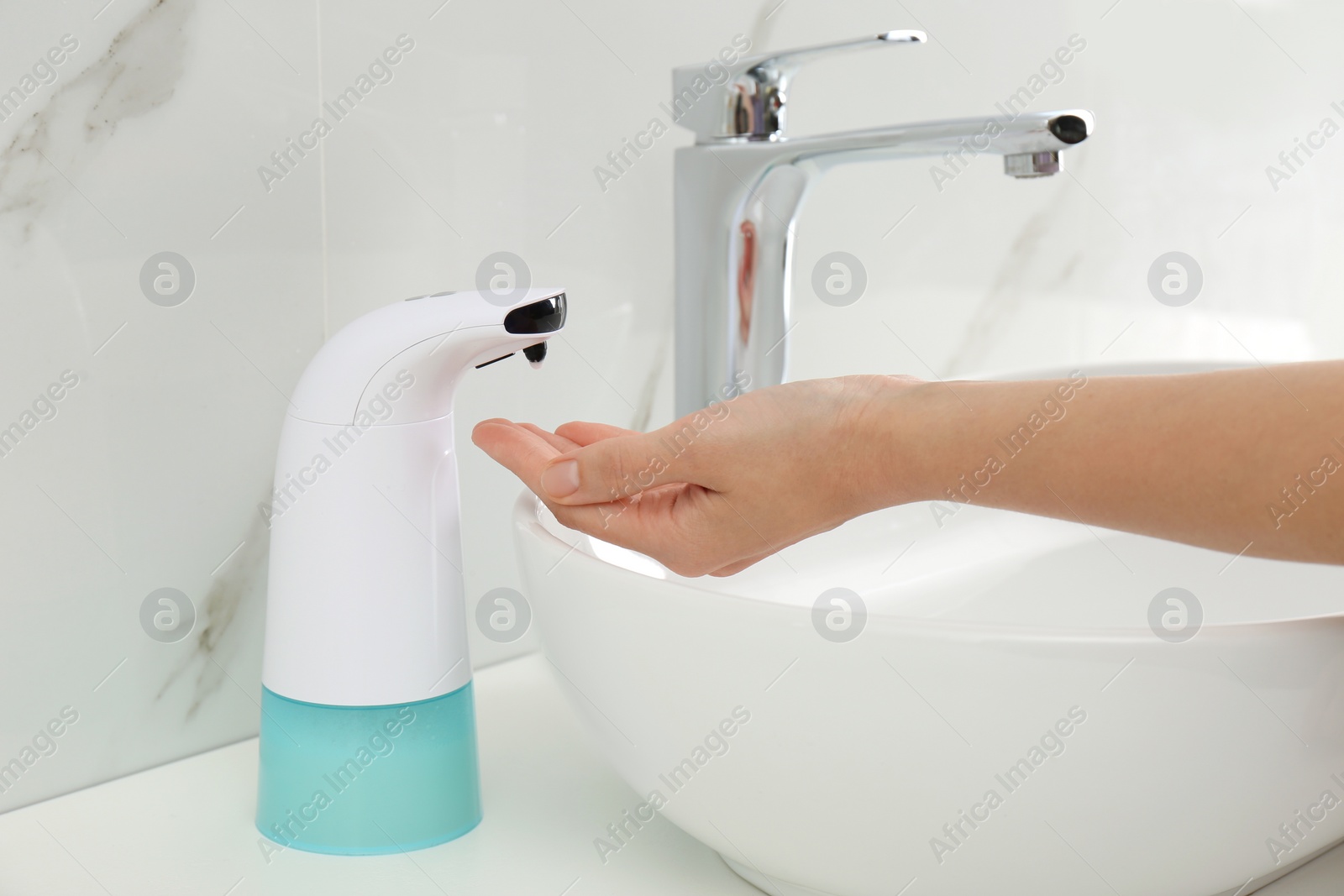 Photo of Woman using automatic soap dispenser in bathroom, closeup