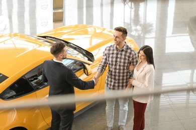 Photo of Young couple buying new car in salon