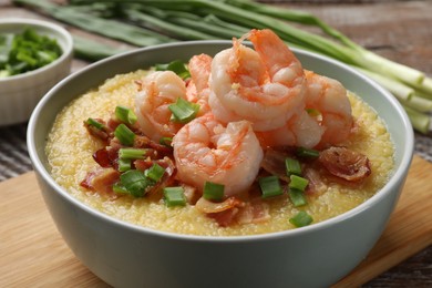 Photo of Fresh tasty shrimps, bacon, grits and green onion in bowl on table, closeup