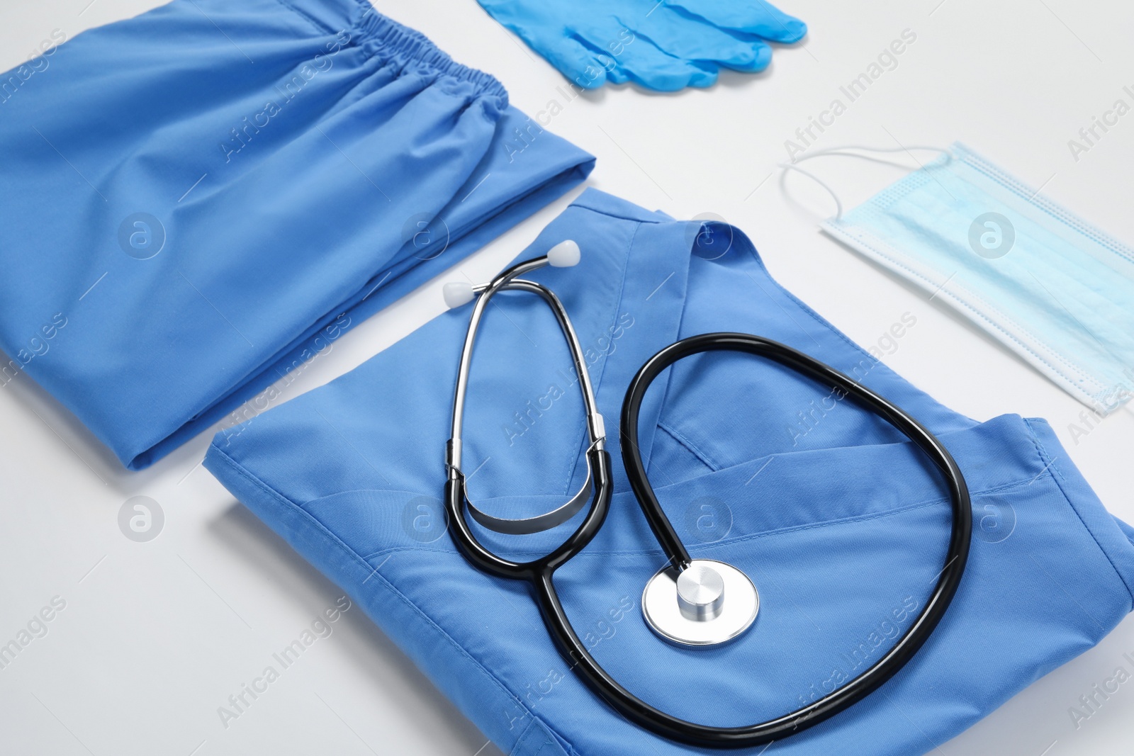 Photo of Medical uniform, mask, gloves and stethoscope on white background