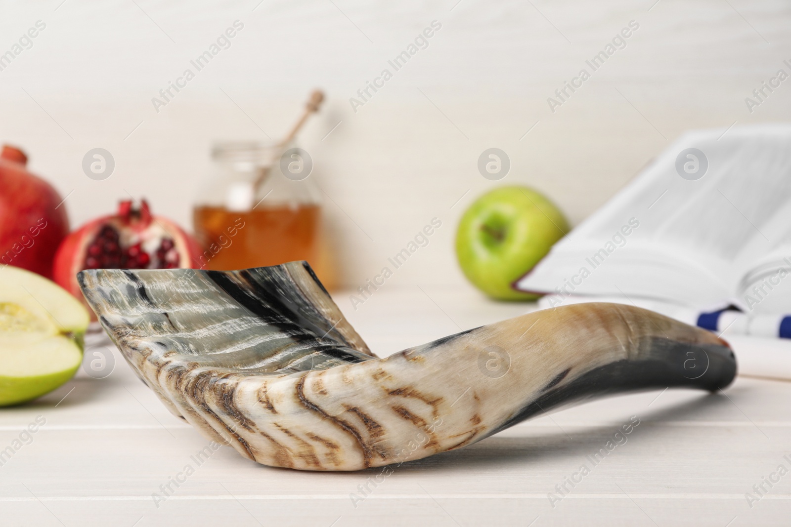 Photo of Shofar and other Rosh Hashanah holiday attributes on white wooden table