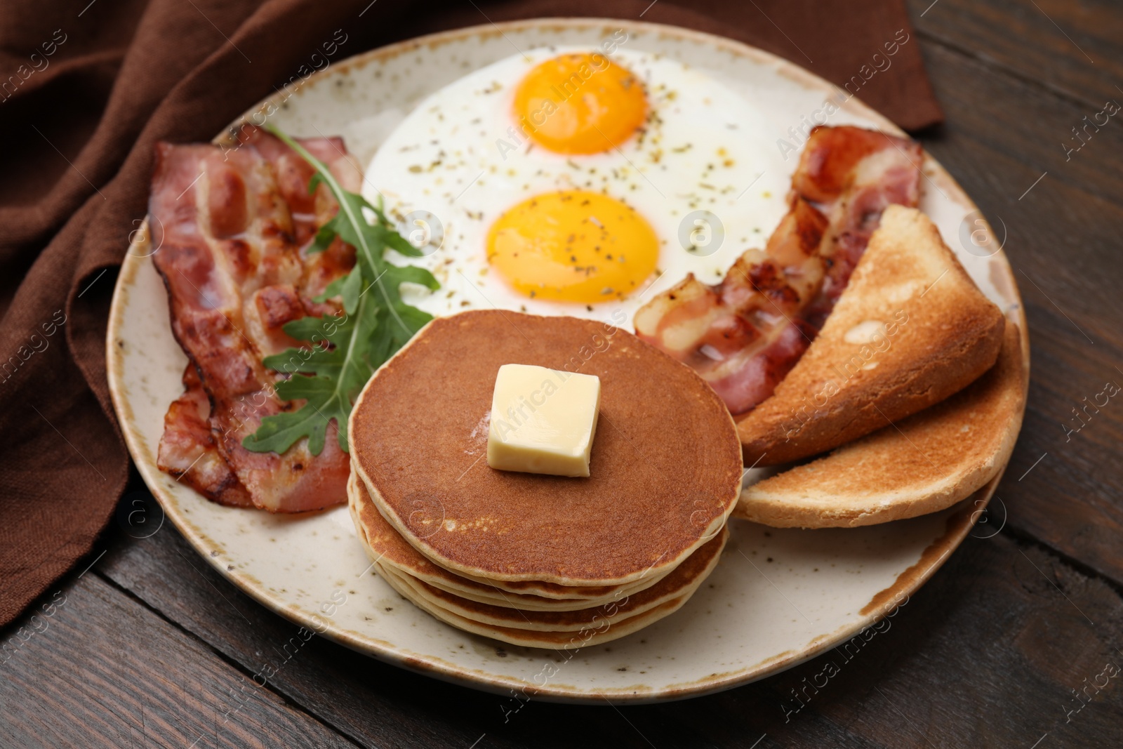 Photo of Tasty pancakes with fried eggs and bacon on wooden table, closeup