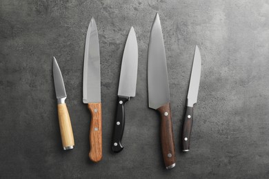 Photo of Many different knives on grey textured table, flat lay