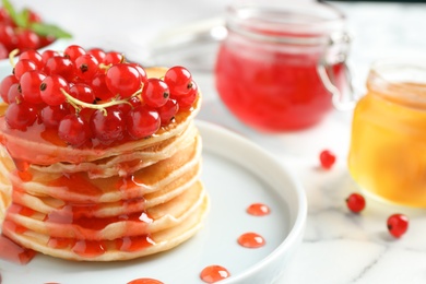 Delicious pancakes with fresh berries and syrup on marble table, closeup