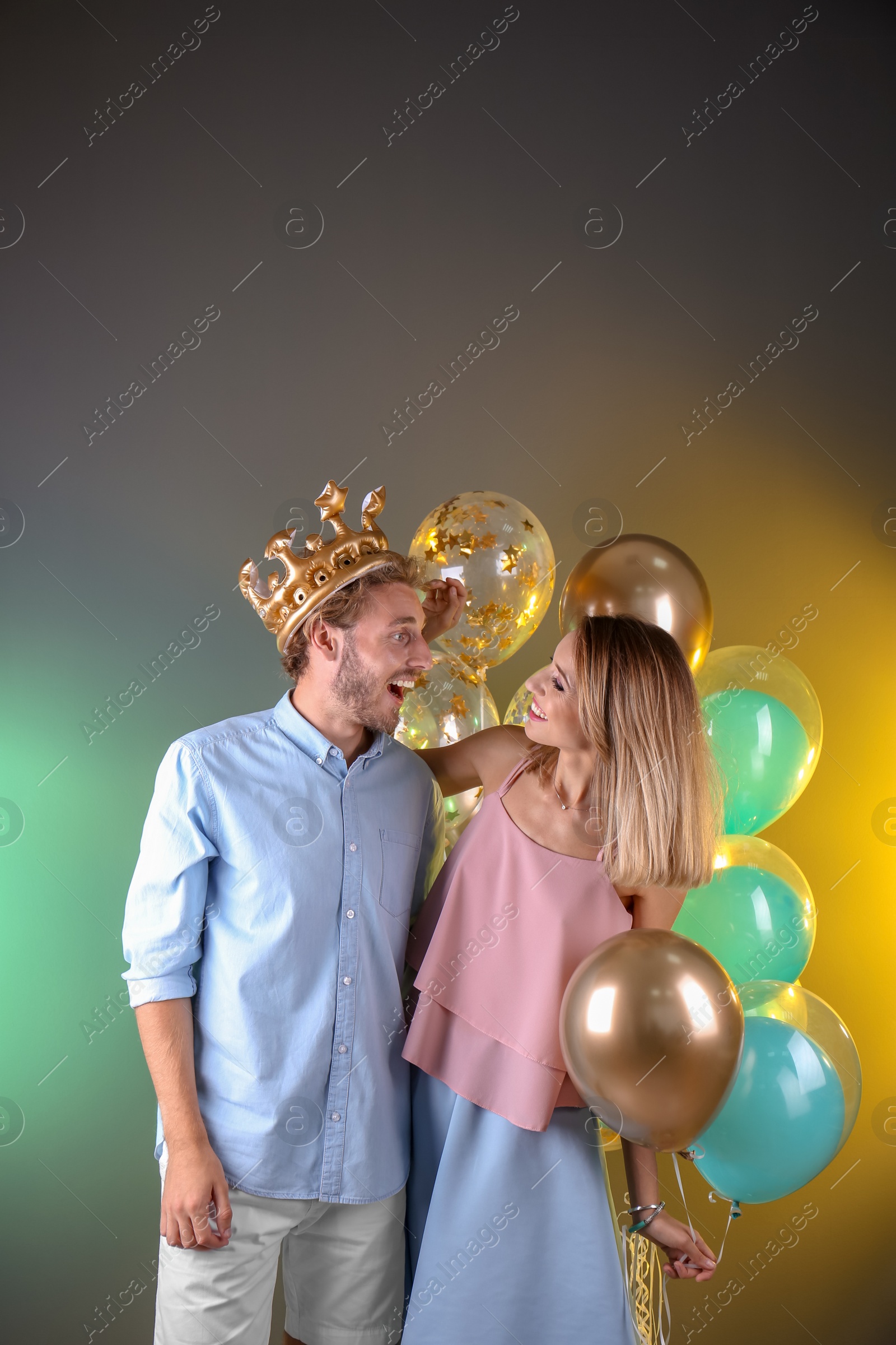 Photo of Young couple with air balloons on color background