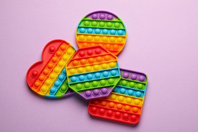 Photo of Rainbow pop it fidget toys on lilac background, flat lay