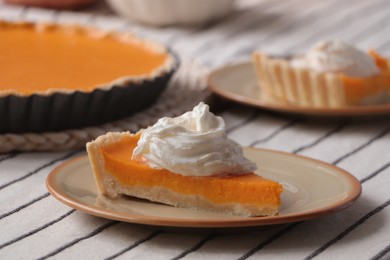 Piece of fresh homemade pumpkin pie with whipped cream on table