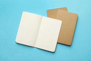 Photo of Stylish kraft notebooks on light blue background, flat lay
