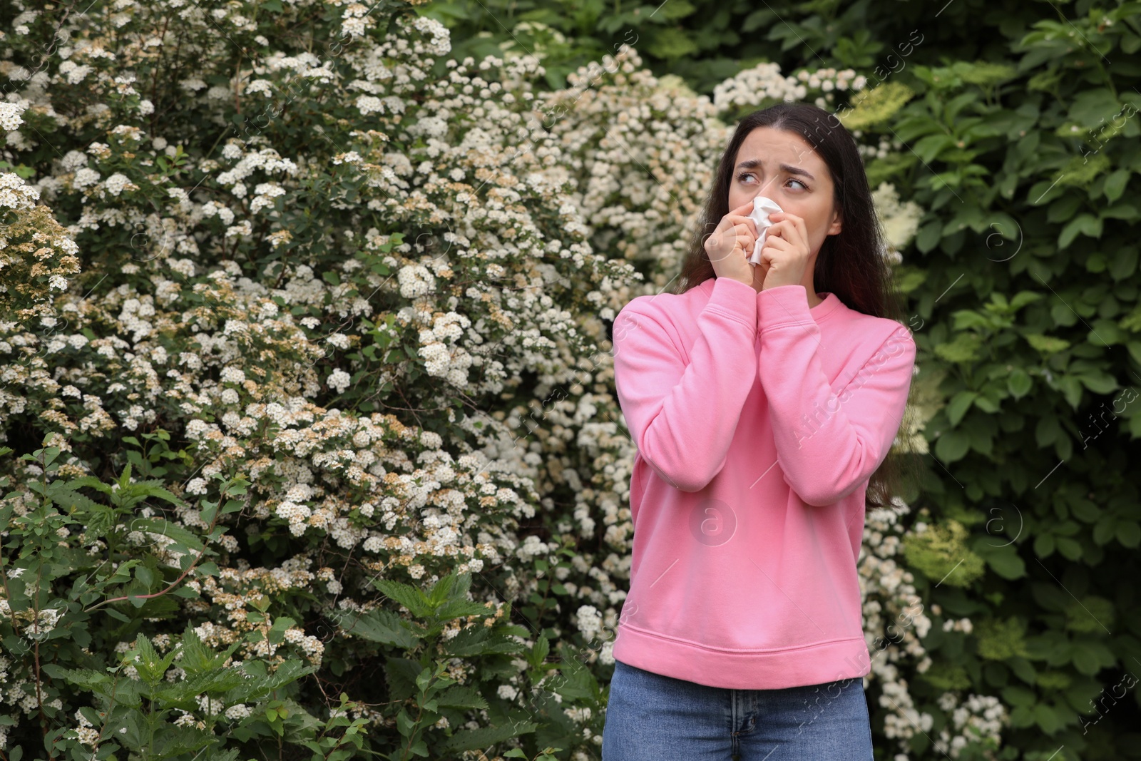 Photo of Woman suffering from seasonal pollen allergy near blossoming tree on spring day