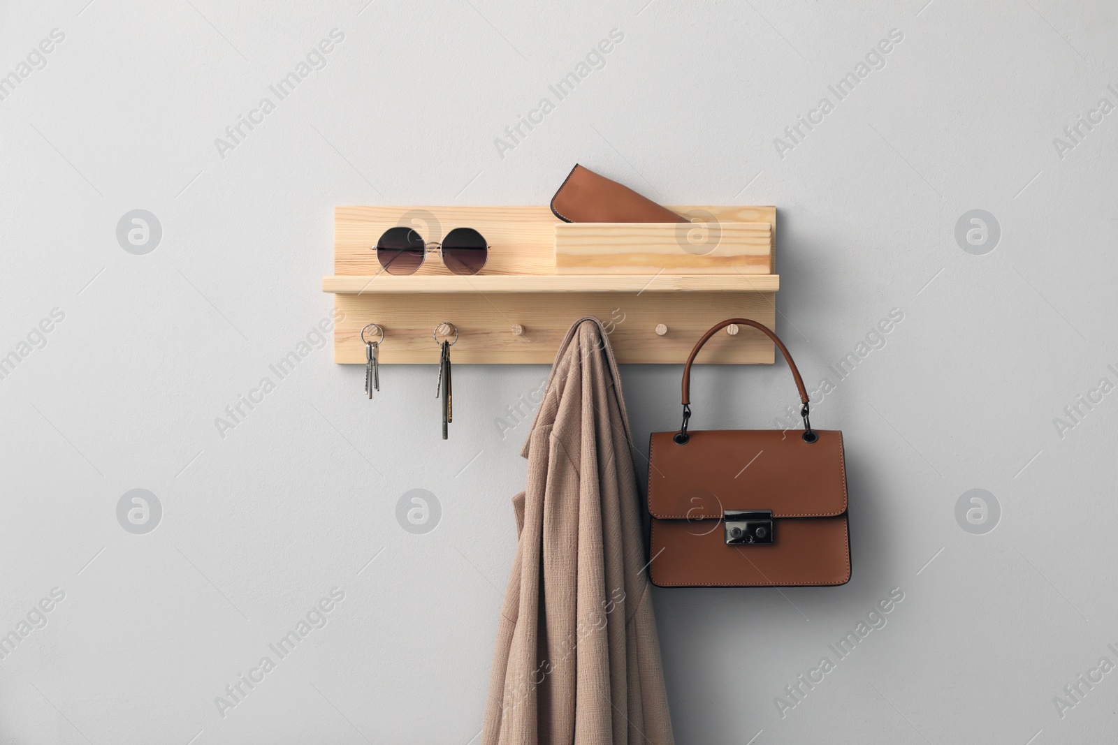 Photo of Wooden hanger for keys with different stuff on light grey wall