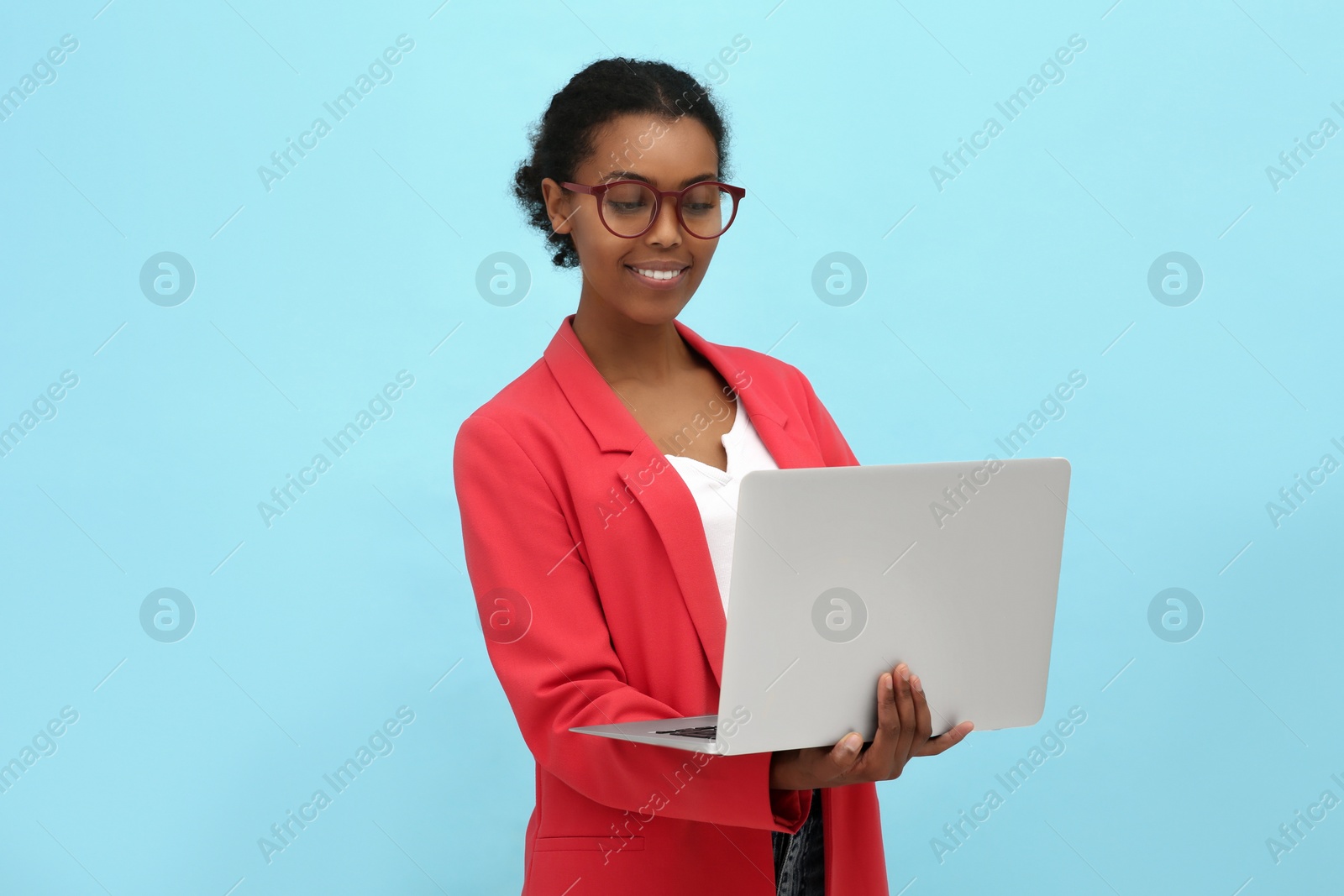 Photo of Smiling African American intern working on laptop against light blue background. Space for text