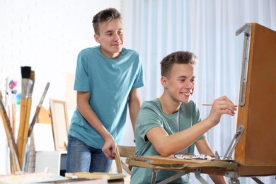 Photo of Teenage twin brothers having painting class in workshop. Hobby club