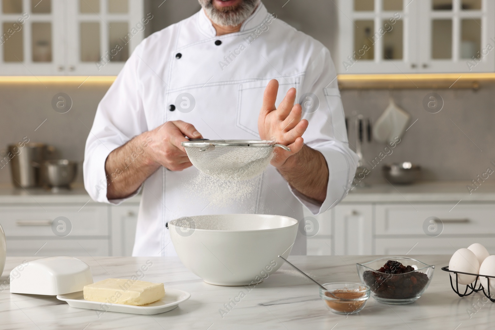 Photo of Professional chef making dough at white marble table indoors, closeup