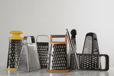 Photo of Different modern graters on white marble table
