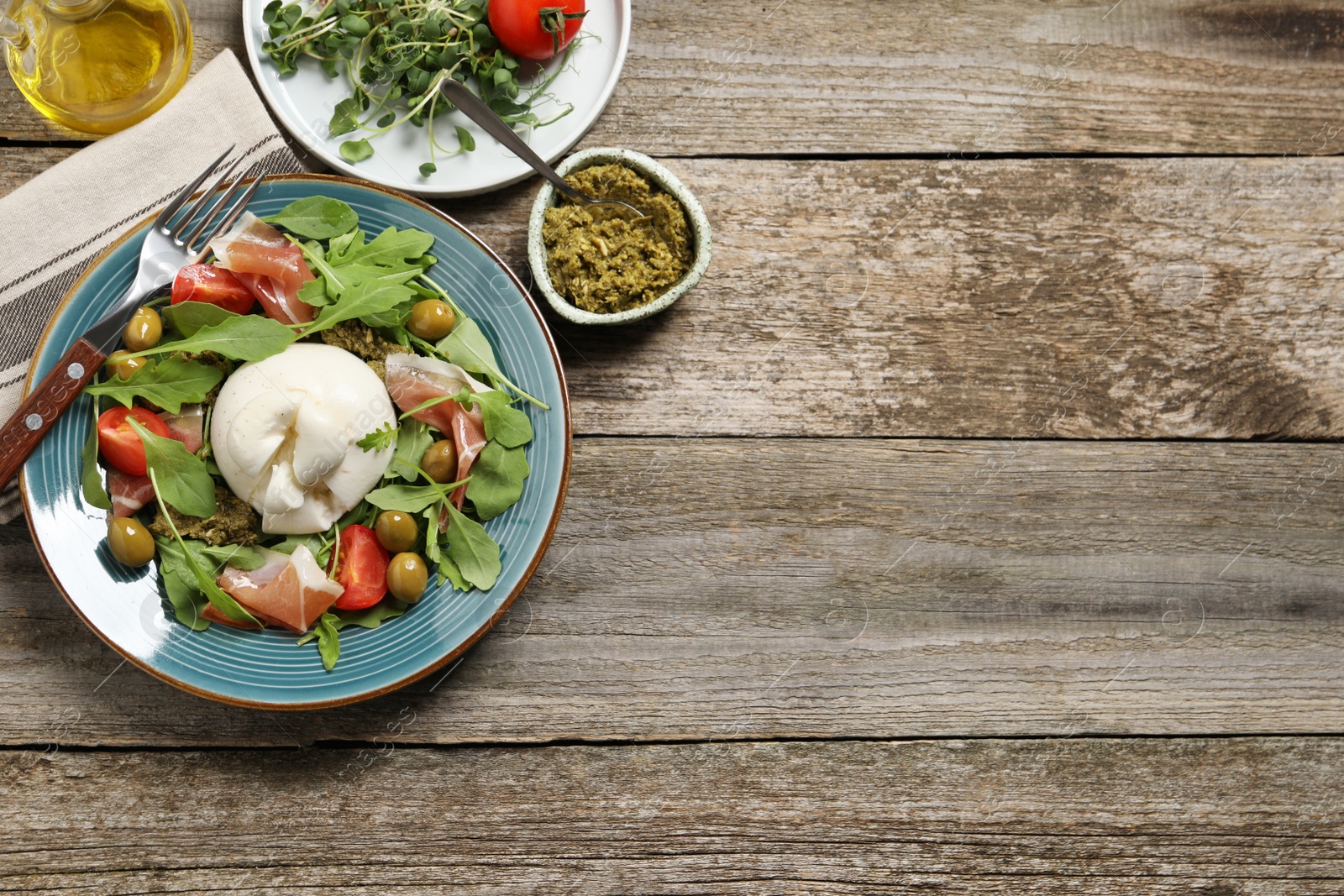 Photo of Delicious burrata salad served on wooden table, flat lay. Space for text