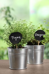 Photo of Aromatic potted thyme and oregano on wooden table