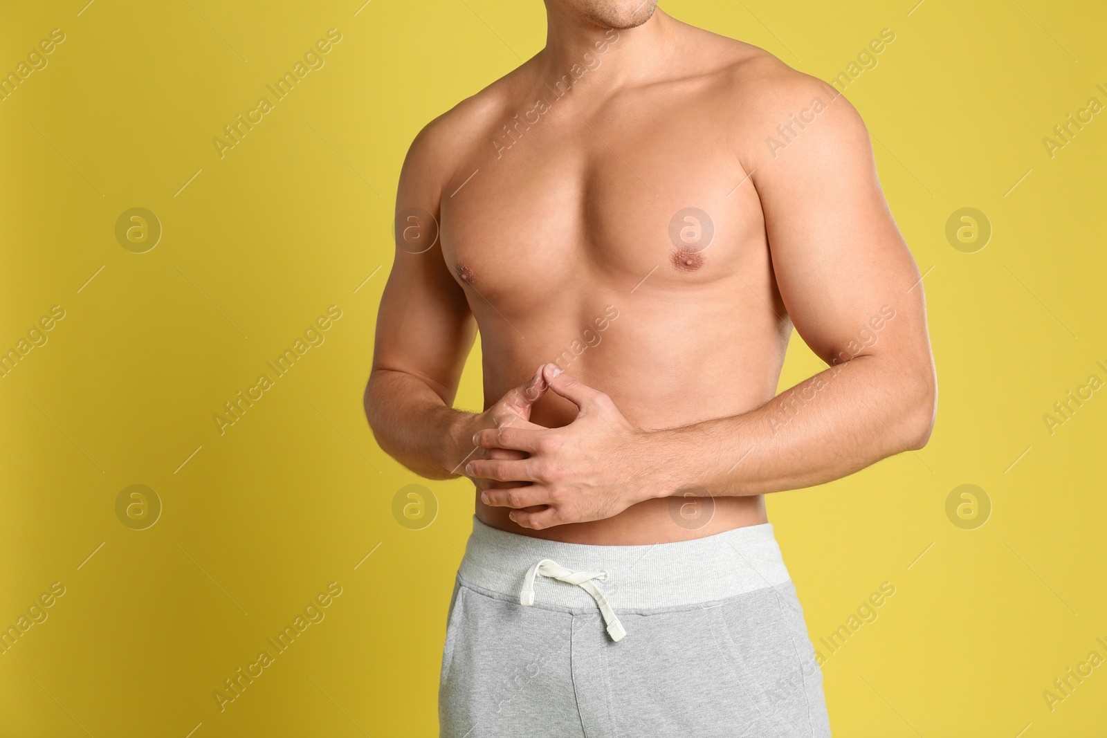 Photo of Man with sexy body on yellow background, closeup