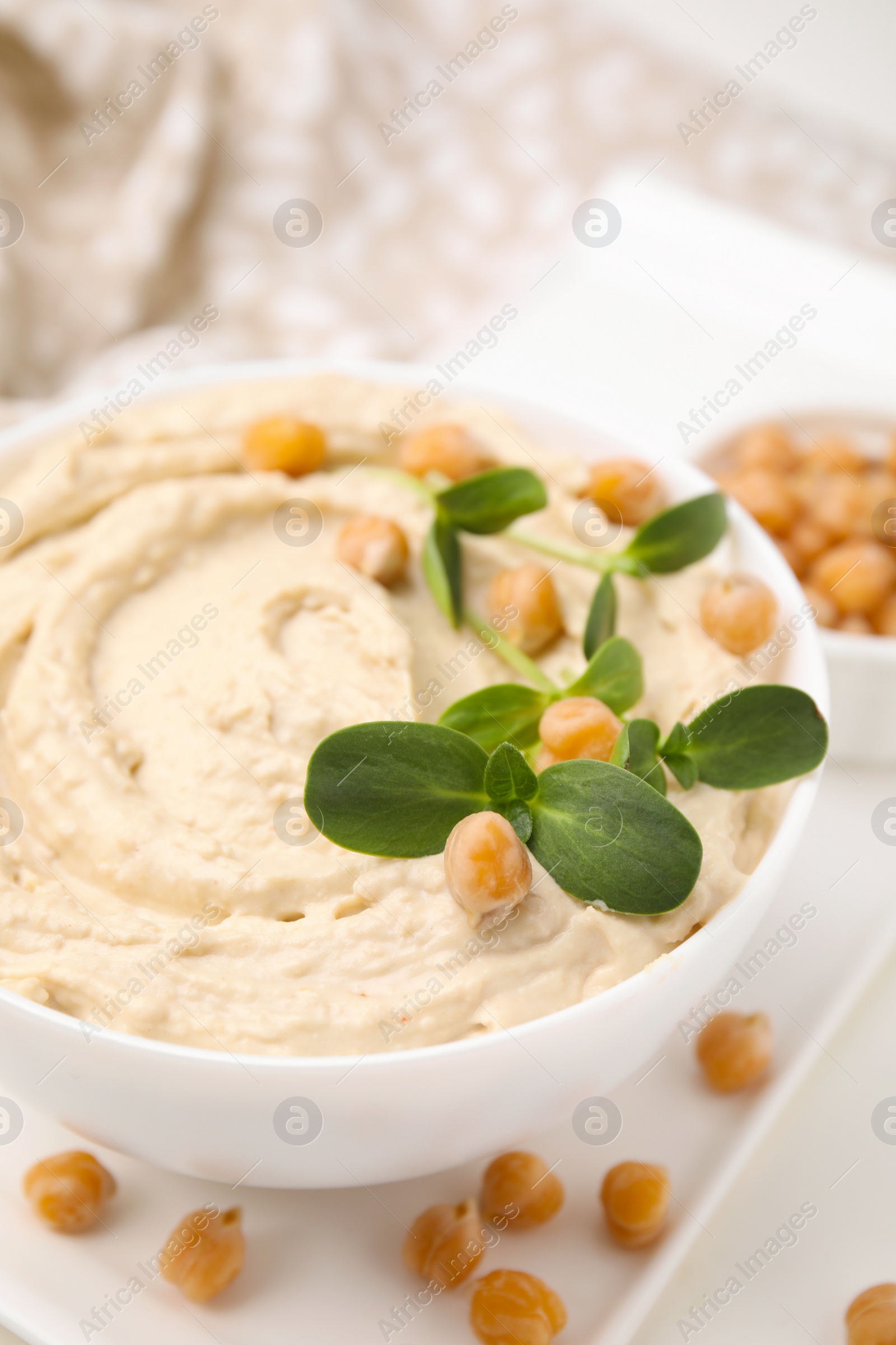Photo of Delicious hummus with chickpeas served on white table, closeup