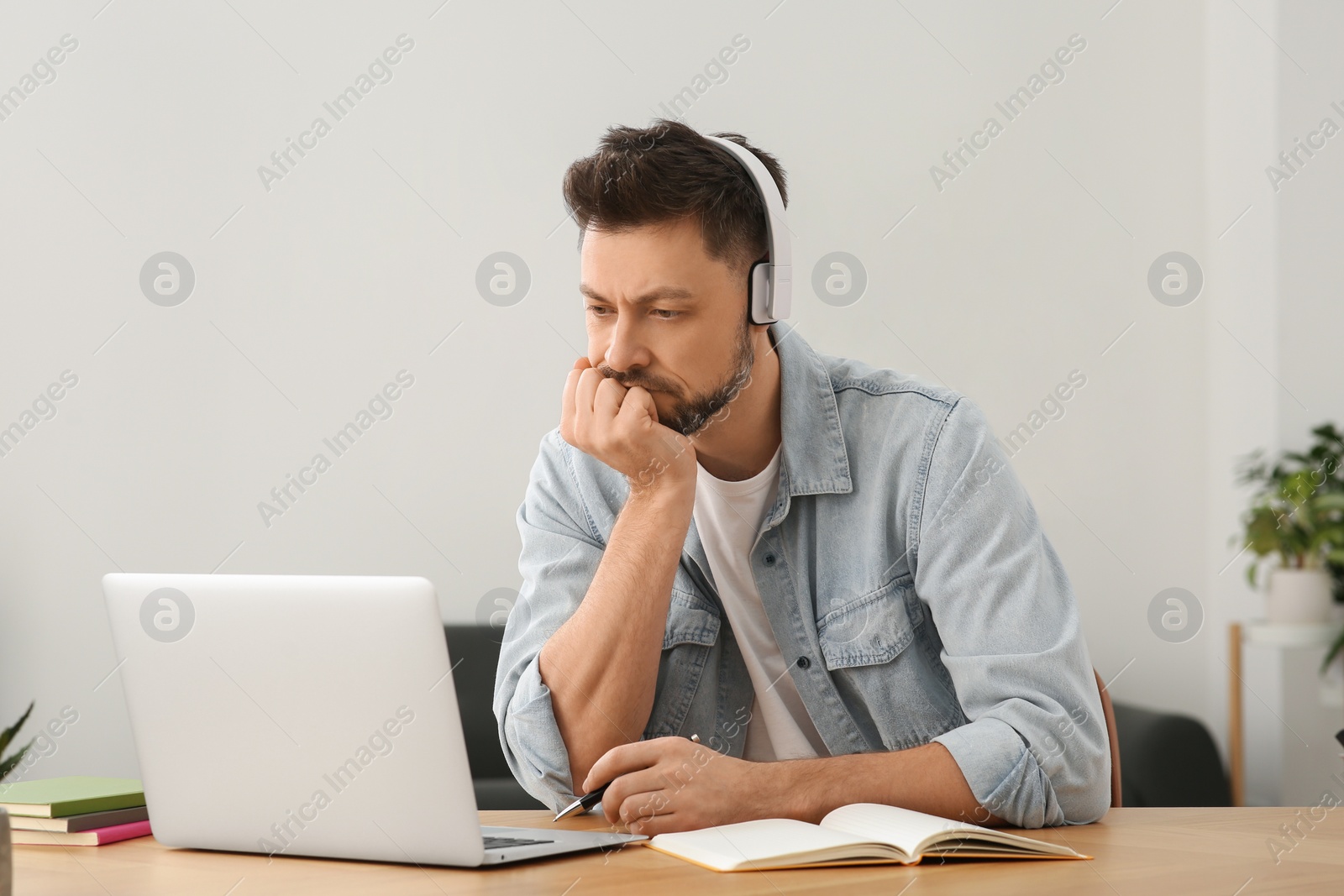 Photo of Man in headphones studying on laptop at home. Online translation course