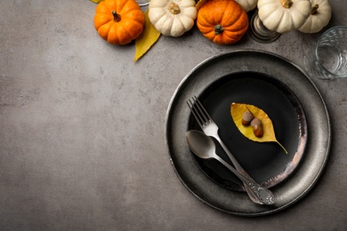 Seasonal table setting with pumpkins and other  autumn decor on grey background, flat lay. Space for text