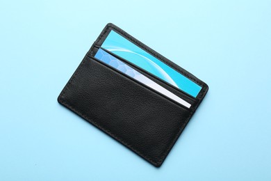 Photo of Leather business card holder with cards on light blue background, top view