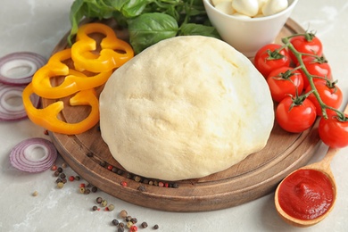 Fresh dough and ingredients for pizza on table