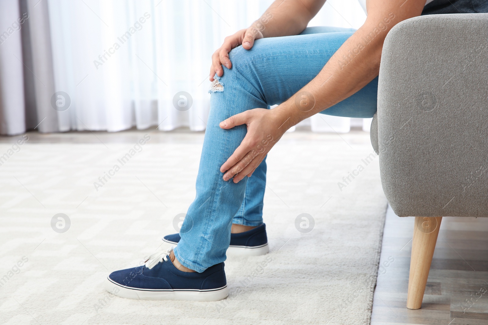 Photo of Man suffering from leg pain at home, closeup. Space for text