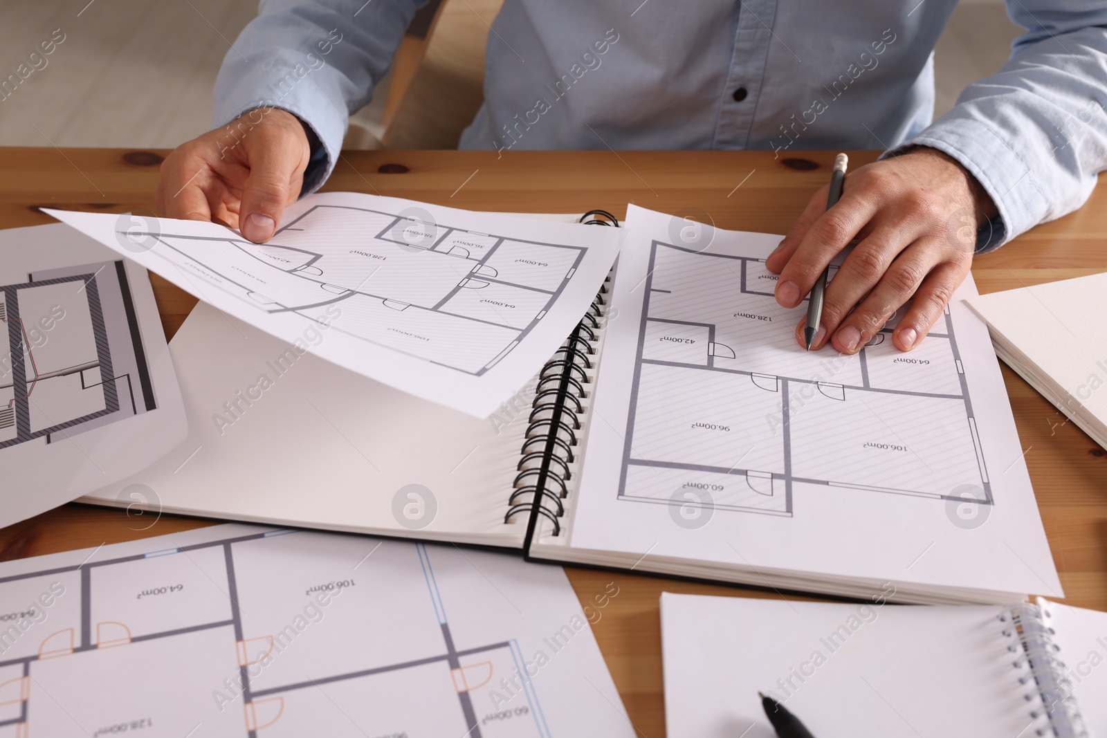 Photo of Man with sketchbook and pencil at wooden table, closeup