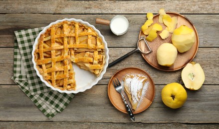 Photo of Tasty homemade quince pie, ingredients, peeler and fork on wooden table, flat lay