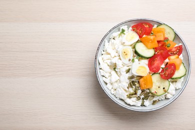 Photo of Fresh cottage cheese with vegetables, seeds and eggs in bowl on wooden table, top view. Space for text